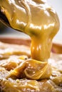 Dulce de leche or homemade caramel dripping from wooden spoon, macro photo of food