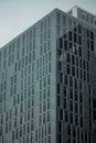 Dull blue glass in front of tall buildings reflecting against the Bangkok sky