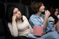 Dull date. Bored young lady with boyfriend watching movie in cinema Royalty Free Stock Photo