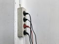 Dull and Dirty Wall Electrical Outlet with Attached Cables Royalty Free Stock Photo