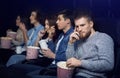 Dull movie. Bored man with company of people in cinema Royalty Free Stock Photo