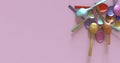 Dull pastel colored metal spoons.Pink background