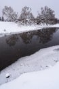 Dull sunless winter landscape. Dark river in ice and trees on snowy banks Royalty Free Stock Photo