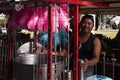 Dumaguete, Philippines - 27 July 2018: Pink cotton candy seller on market stand. Smiling Philippine man selling sweets