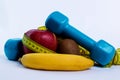 Dumbbell and apple, orange, banana, kiwi white background Royalty Free Stock Photo