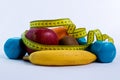 Dumbbell and apple, orange, banana, kiwi white background Royalty Free Stock Photo