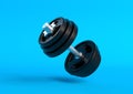 Dumbbell with black plates levitating in air on bright blue background Royalty Free Stock Photo