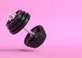 Dumbbell with black plates levitating in air on bright pink background Royalty Free Stock Photo