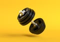 Dumbbell with black plates levitating in air on bright yellow background Royalty Free Stock Photo