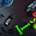 Dumbbell, skipping rope, apple, water bottle, smartphone, headphones and sneakers on black background