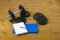 Dumbbell for sport with a towel and a notebook for recording the results, on a wooden background