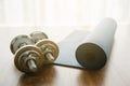 Dumbbells with blue yoga mat on wood floor