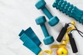 Dumbbells, elastic band, jump rope, roller, apple, measure tape on marble background. Female workout training equipment top view. Royalty Free Stock Photo