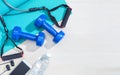 dumbbells, excercise equipment, gym yoga mat, cellphone, earphones, and bottle of water on clean wood floor with strong bright mo Royalty Free Stock Photo