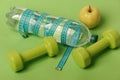 Dumbbells in green color, water bottle, measure tape and fruit Royalty Free Stock Photo