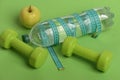 Dumbbells in green color, water bottle, measure tape and fruit Royalty Free Stock Photo