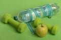 Dumbbells in green color, water bottle, measure tape and fruit Royalty Free Stock Photo