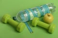 Dumbbells in green color, water bottle, measure tape and fruit Royalty Free Stock Photo