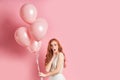 Dumbfounded woman with red hair in dress with air balloons
