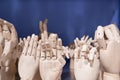 Dummy model wooden human hands gesture set on shelf on blue background close up. Mannequin hand collection closeup.