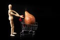 Dummy pushing a shopping cart with a pear on black background. Symbol of commerce