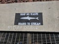 Dump no waste drains to stream anti-pollution sign at storm drain Royalty Free Stock Photo