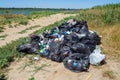 Dump on the river Bank. Garbage in nature. Lots of black bags of waste. Environmental problem of environmental pollution