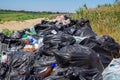 Dump on the river Bank. Garbage in nature. Lots of black bags of waste. Environmental problem of environmental pollution