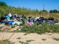 Dump on the river Bank. Garbage in nature. Lots of black bags of waste. Environmental problem of environmental pollution