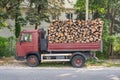 Dump truck with a body full of firewood. Truck loaded with stack of wooden logs to delivery for heating season. Firewood