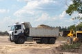 Dump truck with a bunch of land in the back and excavator at the construction site outside the city. Road works