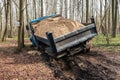 Dump truck car stuck in mud on the road among trees. Blurry mud bad road in the park. ÃÂ¢ruck dump car with sand stopped due to wet Royalty Free Stock Photo