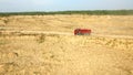 Dump truck driving on rural road. Scene. Top view of truck rides, leaving plumes of dust in dirt road in countryside on