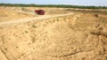 Dump truck driving on rural road. Scene. Top view of truck rides, leaving plumes of dust in dirt road in countryside on