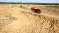 Dump truck driving on rural road. Scene. Top view of truck rides, leaving plumes of dust in dirt road in countryside on