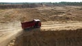 Dump truck driving on rural road. Scene. Top view of truck rides, leaving plumes of dust in dirt road in countryside on