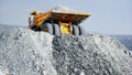 Dump truck on pile of rubble. Rear view of truck standing on pile of rubble and preparing to pour out full body. Heavy Royalty Free Stock Photo