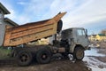 Dump truck with a raised body on a muddy road Royalty Free Stock Photo