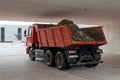 Dump truck with a red cab and body is driving in a tunnel. The body is loaded with earth and stones. Royalty Free Stock Photo