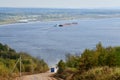 A dump truck rises uphill along a dirt road. In the background is a large river Royalty Free Stock Photo