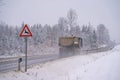 A dump truck on a rural mountain road passing a warning sign for deer crossing Royalty Free Stock Photo