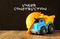 Dump truck toy and safety hat over wooden textured background Royalty Free Stock Photo