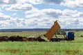 A dump truck unloads manure brought from a livestock farm into the field