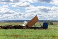 A dump truck unloads manure brought from a livestock farm into the field