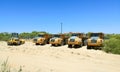 Dump Trucks And Yellow Bulldozer Parked In The Sand Ready For Maintenance Work On The Beach