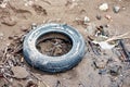 Dumped worn wet car tire on muddy soil surface Royalty Free Stock Photo