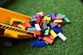 Dumper toy dumping multi colored wooden blocks on green grass