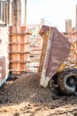 Dumper truck unloading construction gravel, granite and crushed stones at building foundation