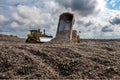 Dumper truck unloading waste on landfill site Royalty Free Stock Photo