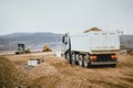 Industrial dumper trucks working on highway construction site, loading and unloading earth. heavy duty machinery activity Royalty Free Stock Photo